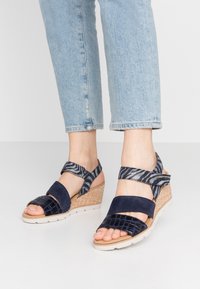 Námořnické wedge sandály s texturovaným textilním svrškem, se zkříženými řemínky a pletenou juteovou mezipodešví. Otevřená špička s vzorovanými akcenty.