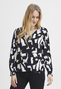Blusa nera con motivo geometrico astratto bianco e azzurro chiaro, maniche lunghe con polsini arricciati, scollatura a V e vestibilità ampia.