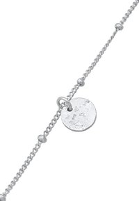 Armband i sterling silver med en vriden kedjedesign och en texturerad cirkulär medaljong fäst. Har små runda dekorationer längs kedjan.