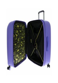 Valise rigide violette avec un intérieur noir orné de graphiques jaunes, y compris des icônes. Dispose d'une poignée rétractable et de roues.