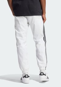 Vita sportbyxor i lätt material med svarta sidosträck. Muddade anklar och kombineras med svartvita sneakers.