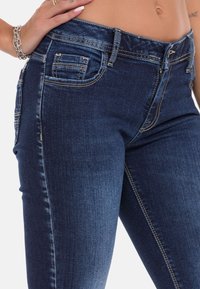 Donkerblauwe denim jeans met een slim fit ontwerp, zichtbare stiksels, voor- en achterzakken en een middelhoge tailleband.