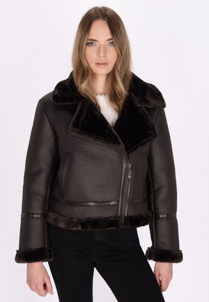 Bruine faux leren jas met een kraag en manchetten van nepbont. Voorzien van een ritssluiting aan de voorkant en twee zijzakken. Gelaagd oppervlakte-details.