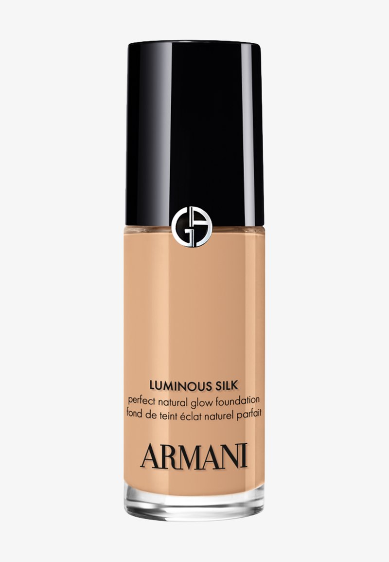 Flacon de fond de teint Armani Luminous Silk natural glow avec bouchon noir et logo argenté sur fond beige clair.