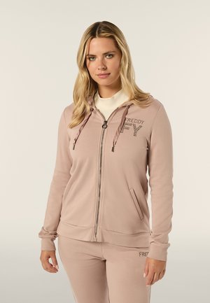 Sweatshirt zippé rose clair en matériau doux, doté d'une capuche, de poches avant et du logo "FREDDY" rehaussé d'un subtil accent de strass.