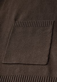 Brązowa dziana tkanina o teksturowanej powierzchni. Posiada kieszeń naszywaną oraz ściągacze na krawędzi kieszeni. Miły w dotyku i ciepły wygląd.