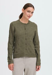 Oliivinvihreä neulecardigan, jossa on teksturoidut kuviot, pyöreä pääntie ja nappisulku. Pitkät hihat ja resorit täydentävät muotoilua.