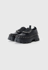 Pantofi cu platformă negri, din piele sintetică, cu studuri decorative și un accent din lanț, având o talpă groasă și texturată.