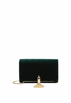 Clutch de terciopelo verde oscuro con correa de cadena dorada y borla dorada decorativa en la solapa frontal, aislada sobre fondo blanco.