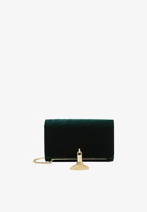 Clutch de terciopelo verde oscuro con correa de cadena dorada y borla dorada decorativa en la solapa frontal, aislada sobre fondo blanco.