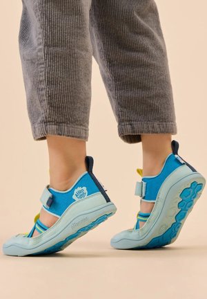 Blue multi-strap shoes with a textured sole and a light blue accent. Velcro closure and logo prominently displayed on the heel.