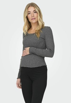 Gray long-sleeve ribbed top with a scalloped neckline and hem, paired with black ribbed pants, highlighting texture and fitted silhouette.