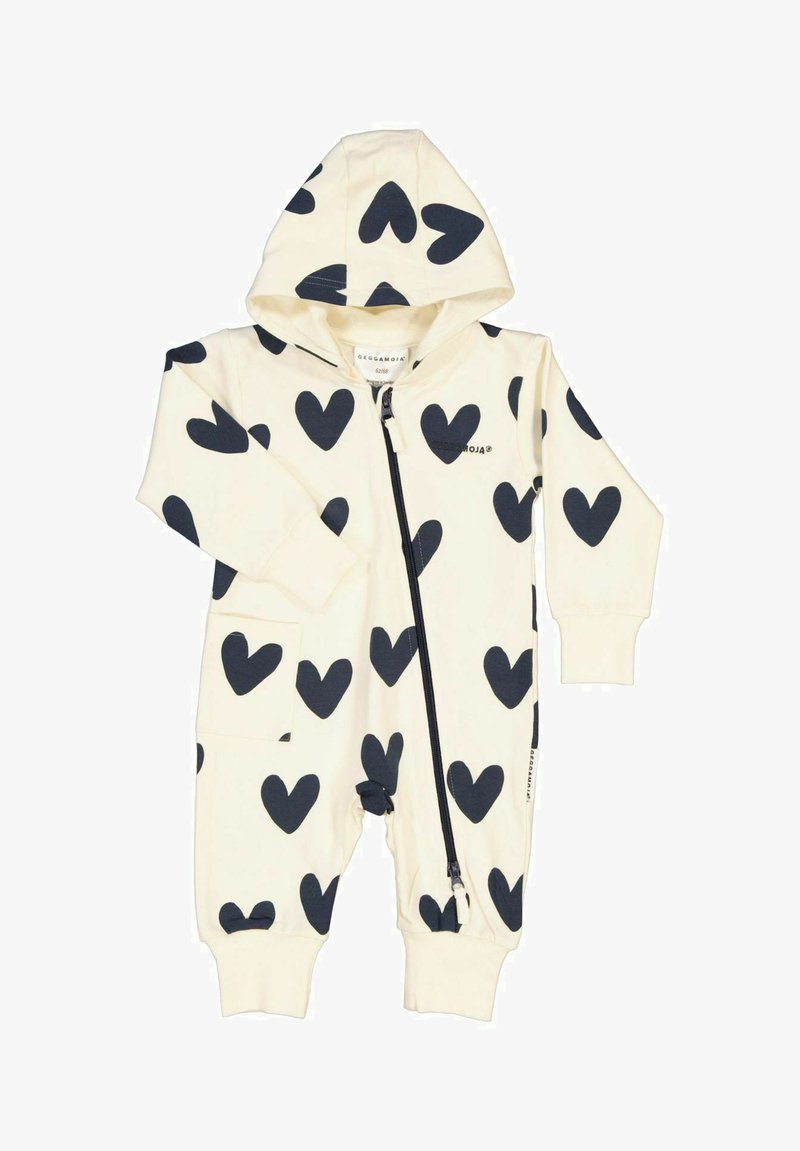 Vauvan vaalean kermanvärinen haalari, jossa on huppu, mustien sydänten kuviointi, etuvetoketju ja ribbireunat. Pehmeää puuvillakangasta, jossa on taskut.