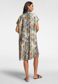 Prodyšné, vzorované šaty s diamantovým motivem v zelené, modré a oranžové. Krátké rukávy a límeček. Lehce jemná tkanina s volným střihem.