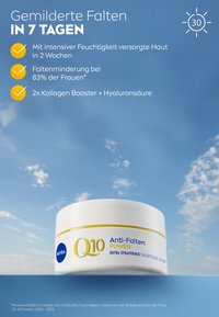 White round jar with a yellow accent band. Label reads "Q10 Anti-Falten POWER." Creamy texture visible. Sky backdrop, emphasizing product.