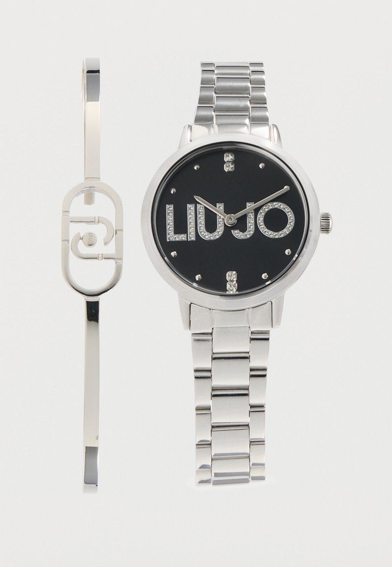 Montre en métal argenté avec cadran noir et logo "LIU JO" orné de cristaux, associée à un bracelet argenté assorti présentant une découpe ovale.