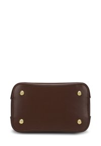 Bruine leren tas met een rechthoekige vorm, afgeronde hoeken en goudkleurige hardware op de onderste hoeken; gladde textuur.