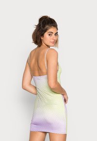 Vestido justo com alças finas, padrão de bolinhas em degradê de verde a lavanda, textura suave e design de costas baixas.