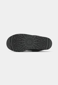 Black rubber outsole featuring a detailed traction pattern, smooth surface, and a circular logo at the center.
