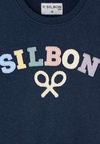 Sudadera azul oscura con letras bordadas en varios colores que dicen "SILBON" y un motivo de tijeras blancas cosido en la parte inferior.