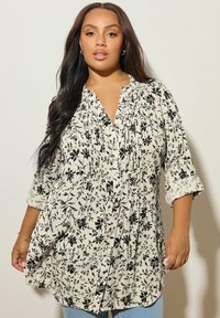 Blusa a fantasie floreali, con bottoni, di colore crema con motivi botanici neri, maniche sopra il gomito e texture morbida. Adatta per un look informale.