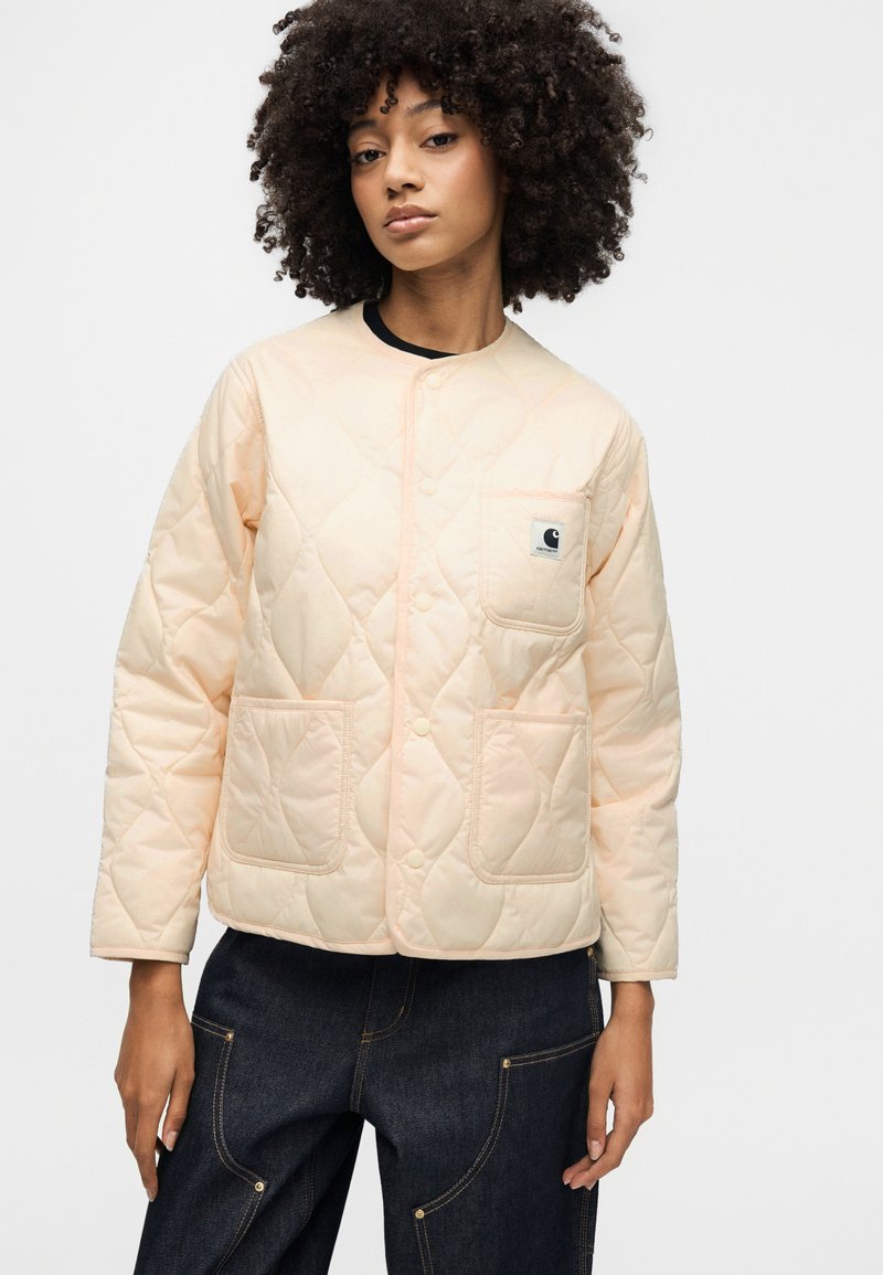 Giacca trapuntata in morbido pesca, con scollo tondo, bottoni automatici, due tasche applicate frontali e una piccola etichetta con logo sul petto.