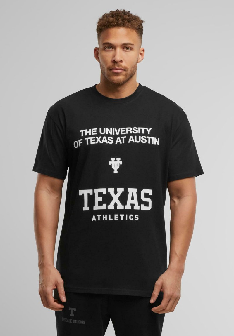 Sort bomulds T-shirt med hvid tekst: "THE UNIVERSITY OF TEXAS AT AUSTIN" og "TEXAS ATHLETICS" i fede, blokbogstaver.