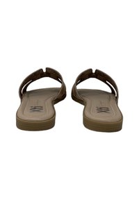 Sandalias marrones con suela plana, que presentan dos correas cruzadas y una plantilla acolchada. Lados suaves y un logotipo sutil en la plantilla.