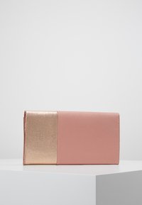 Růžová peněženka s hladkým povrchem, na jedné straně s metalickým zlatým akcentem a designem na přeložení. Obdélníkový tvar, minimalistický styl.