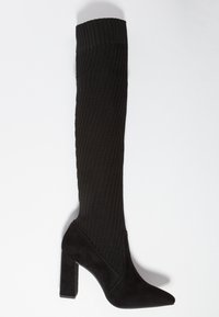 Botas negras hasta la rodilla con parte superior de tela acanalada y tacón de ante texturizado. Presenta una punta afilada y un tacón cuadrado grueso.