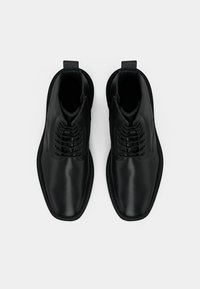 Black leather ankle boots with a smooth surface, round toe, and lace-up front. Features subtle stitching and a pull tab on the back.