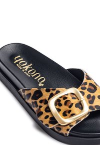 Sandal in stampa leopardata con soletta nera testurizzata, una vistosa fibbia dorata e suola in gomma nera. Fatto in Spagna.