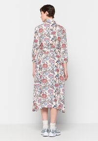 Florales Midikleid aus leichtem Stoff mit rosa und blauen Mustern auf einem cremigen Hintergrund. Mit einem Gürtel in der Taille und Dreiviertelärmeln.