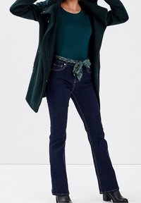 Dark green long coat, teal shirt, dark blue jeans with a tied patterned belt. Black heeled ankle boots. Smooth textures, tailored fit.