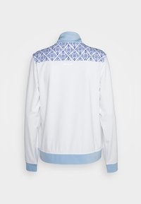 Bílá bunda s modrým límcem a manžetami, která má geometrický modrý vzor přes horní část zad. Materiál se jeví jako hladký a jemný.