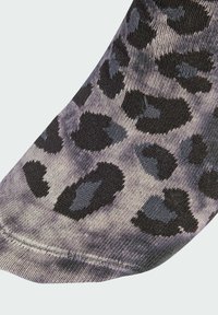 Leopardi kuosis kangas, jossa mustia pilkkuja vaaleanharmaalla taustalla. Sitrusmateriaali, jossa näkyviä tikkejä reunassa.