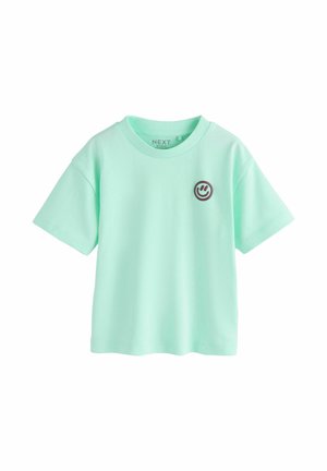 Mintgrøn kortærmet t-shirt med et lille mørkt smiley-emblem på venstre bryst og rund halsudskæring.
