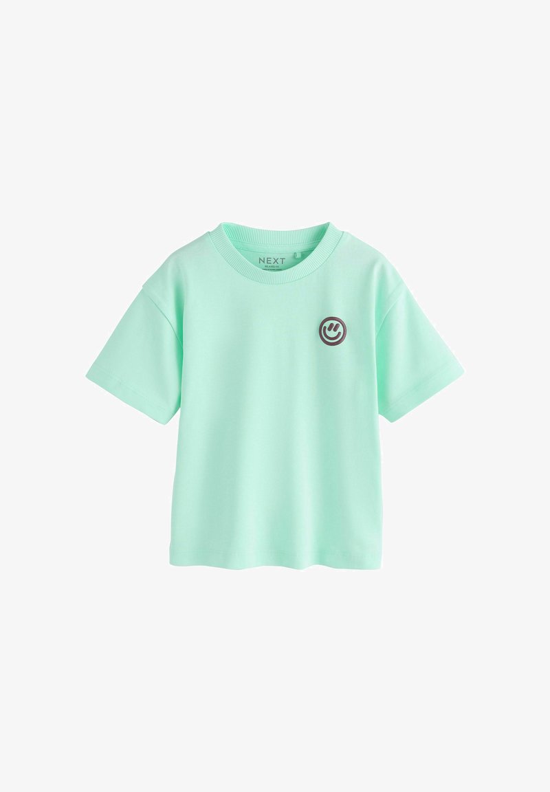 T-shirt à manches courtes vert menthe avec un petit emblème de smiley foncé sur le côté gauche de la poitrine et un col rond.