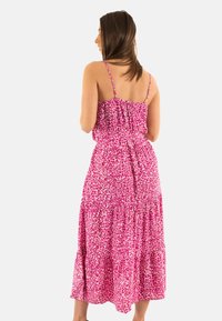 Robe maxi à imprimé animal rose avec bretelles spaghetti réglables, buste froncé, taille élastique et jupe à volants. Tissu léger.