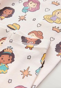 Tessuto in cotone per pigiami con uno sfondo crema che presenta colorate principesse dei cartoni animati e stelle in una stampa giocosa. Accentuato con dettagli stampati.
