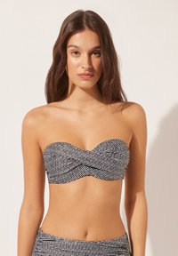 Bandeau bikini-top i sort og hvidt vævet stof. Har et snoet design, glat tekstur og støtte uden stropper.