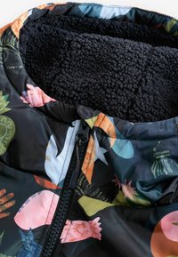 Topptegumoega musta mustriga, kus on värvilised lillelised ja geomeetrilised kujundused; pehme tume vooder ja lukuga lukk.