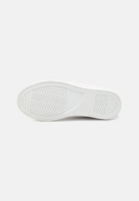White sneaker sole, featuring a textured rubber surface with zigzag pattern for grip, smooth edges, and curved shape.