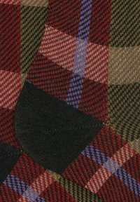 Calze lavorate a maglia con un motivo a quadretti multicolore nei toni del rosso, verde, marrone e viola. Texture morbida con rinforzo sul tallone e sulla punta in nero.