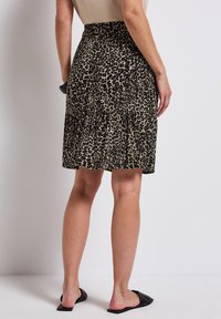 Leopardskinnad kjol med volangnederkant, tillverkad av mjukt tyg, med elastisk midja, i beige och svarta nyanser.