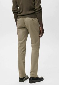 Khaki chinos med slim fit, med en mjuk bomullstextur, bakfickor och minimalistisk design. Matchas med svarta skor.