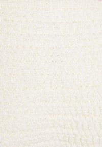 Tecido de malha branca com uma superfície suave e texturizada, apresentando um padrão subtil e elevado. O material parece confortável e leve.