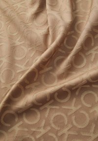 Tessuto beige con un motivo testurizzato di forme sovrapposte a "O" e "X", caratterizzato da una finitura liscia e una leggera lucentezza.