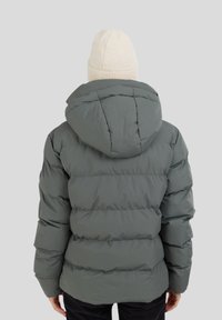 Harmaa puhallus takki vaakasuorilla ompeleilla ja hupulla. Pehmeä kangas, jossa on istuva muotoilu, yhdistettynä vaaleanbeigeen neulottuun pipoon.