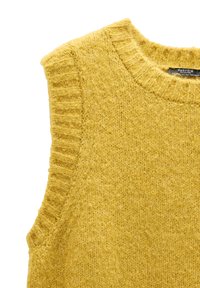Żółty dziergany sweter bez rękawów z prążkowanym dekoltem i wykończeniem otworów na ramiona, o miękkim i teksturowanym wyglądzie.